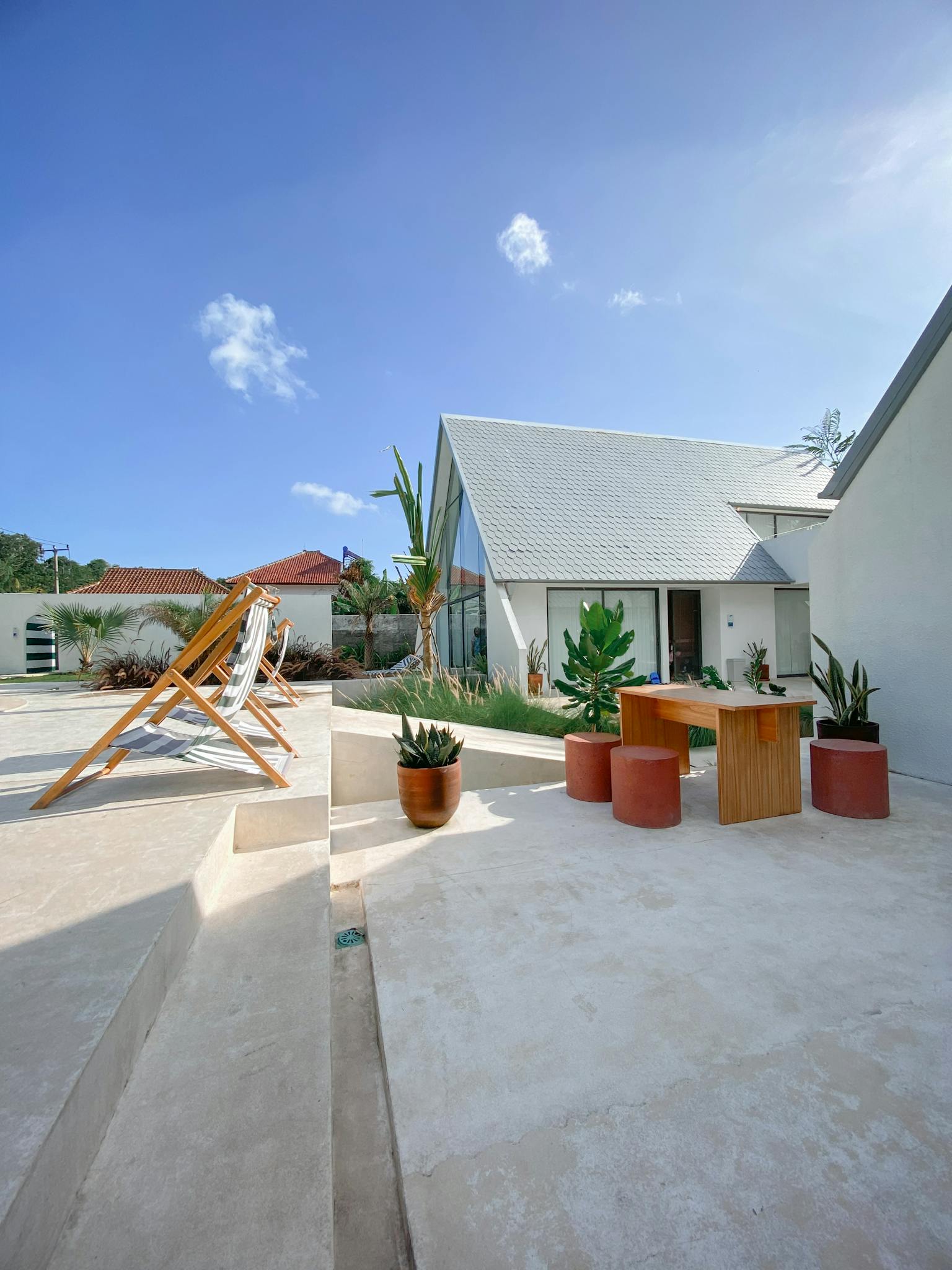 Contemporary outdoor patio with sunbeds and planters, ideal for relaxation.