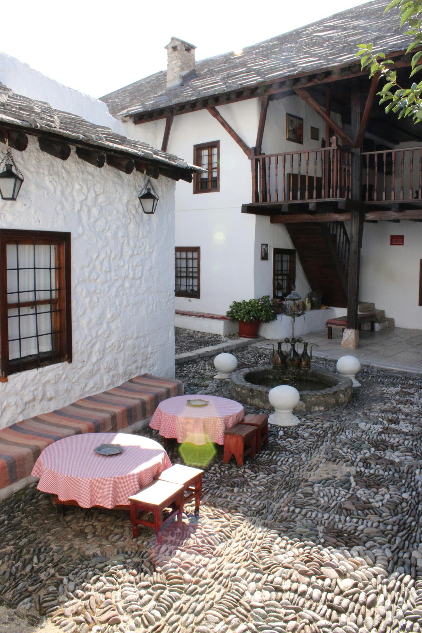 Rustic Mediterranean courtyard with stone floor, cozy seating, and traditional architecture. Inviting and serene setting.